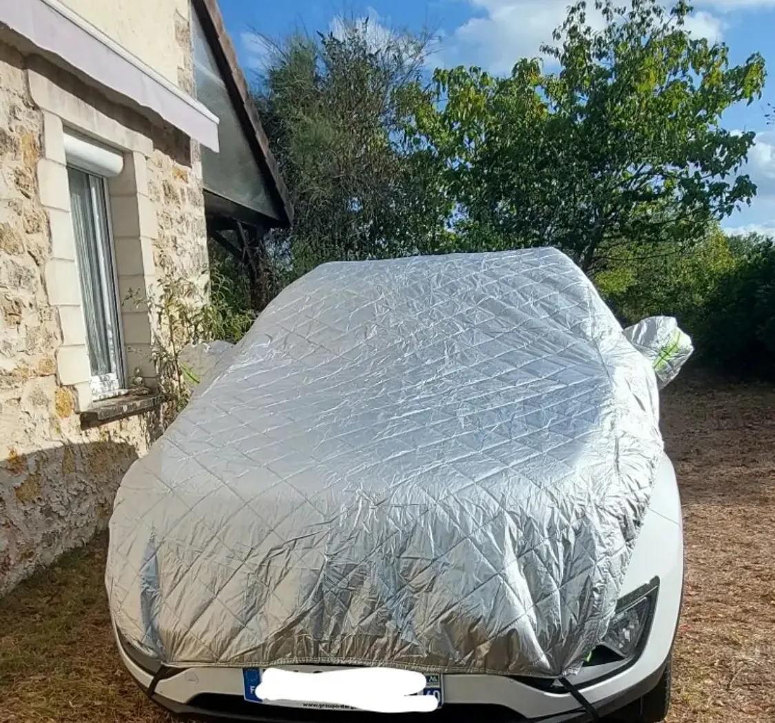 Auto bianca coperta dal telo copriauto in campagna