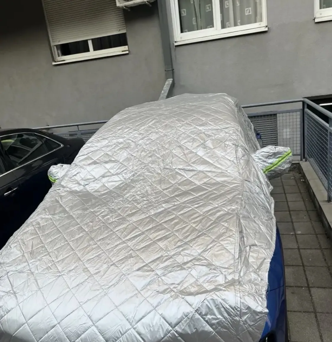 Auto protetta dal telo copriauto in un parcheggio condominiale